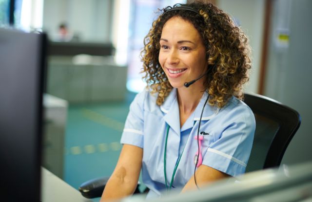 NHS Staff Member In An Office Behind A Desk Answering A Call